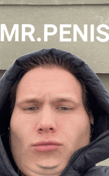 a man wearing a hooded jacket stands in front of a sign that says mr penis