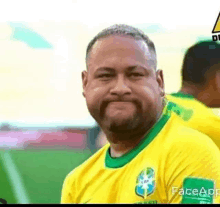 a man with a beard wearing a yellow and green soccer jersey is smiling .