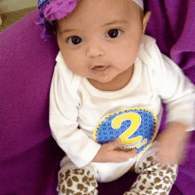 a baby wearing a white shirt with the number two on it