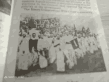 a black and white photo of a group of people standing in a line .