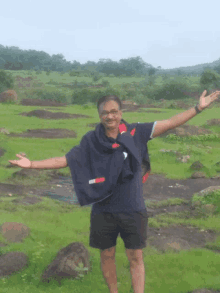 a man standing in a field with his arms outstretched wearing a tommy hilfiger shirt