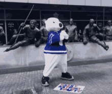 a polar bear mascot stands in front of a statue of a hockey player and a sign that says happy hockey day youth