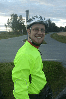 a man wearing a helmet and a bright yellow jacket smiles for the camera