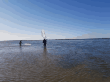 two people standing in a body of water with one holding a net