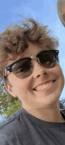 a young boy wearing ray-ban sunglasses is smiling for the camera