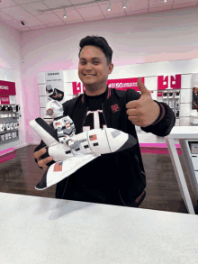 a man holding a model of a space shuttle with the letter t on it