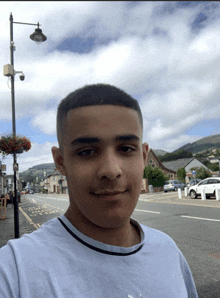 a young man in a white shirt is standing in front of a street