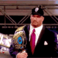 a man in a suit and tie is holding a wrestling belt