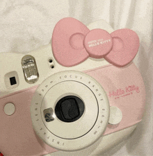 an instax mini hello kitty camera with a pink bow on it