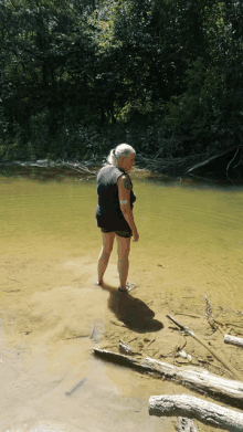 a woman with a tattoo on her arm is standing in a river