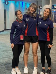 three girls are posing for a picture and one has a lanyard around her neck that says ' sydney ' on it