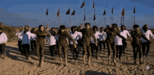 a group of people are dancing on a sandy beach with flags in the background and a watermark that says smcsd