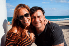 a man and woman are posing for a picture on the beach