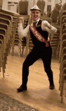 a man wearing a sash that says new year 's eve is dancing in front of a stack of chairs