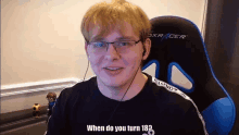 a man wearing glasses and headphones is sitting in a blue and black dxracer gaming chair .