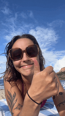 a woman laying on a beach giving a thumbs up