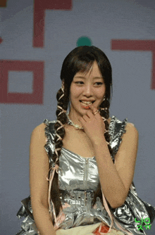 a woman in a silver dress with braids on her hair is smiling