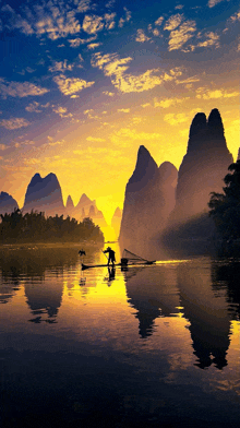 a man in a boat on a lake at sunset with mountains in the background