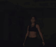 a woman in a crop top is standing in the dark .