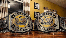 two aew tag team championship belts are on display on a table