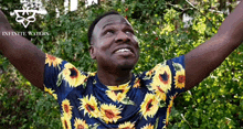 a man wearing a sunflower shirt with infinite waters written on the bottom