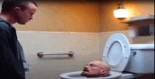 a man is standing next to a toilet with a head in it