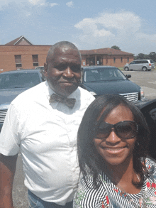 a man in a bow tie and a woman wearing sunglasses pose for a picture