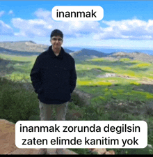 a man in a black jacket stands in front of a landscape with the word inanmak on top