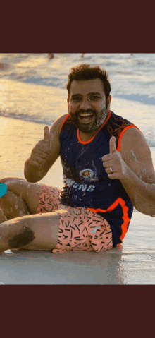 a man is giving a thumbs up on the beach