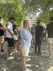 a woman in a blue shirt stands in a line of people