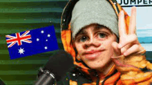 a young boy is making a peace sign in front of a microphone and a flag .