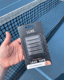 a hand holds a package of luxe pickleball lead tape