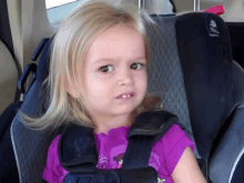 a little girl is sitting in a car seat and making a face