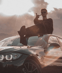 a man sitting on top of a car with his feet on the windshield