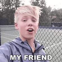 a young boy is standing in front of a chain link fence with the words " my friend " written above him