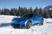 a blue sports car is parked in the snow with trees in the background