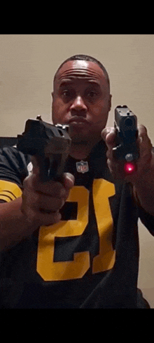 a man in a pittsburgh steelers jersey is holding two guns .