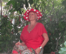 a woman wearing a red shirt and polka dot hat smiles