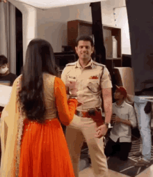 a man in a police uniform is shaking hands with a woman in an orange dress .