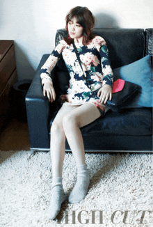 a woman in a floral dress sits on a couch with high cut written on the carpet