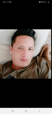 a man is laying on a bed and looking at the camera while wearing earrings .