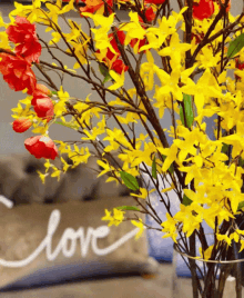 a pillow with the word love written on it sits next to a vase of flowers