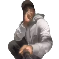 a man wearing a hat and a hoodie is kneeling down and smoking