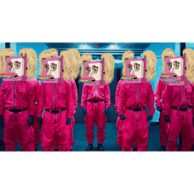 a group of people in pink jumpsuits with boxes on their heads that say ' squid game ' on them