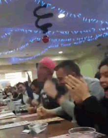 a group of people are sitting at a table in a restaurant with a christmas ball hanging from the ceiling