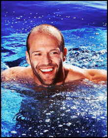 a shirtless man is smiling while swimming in the water