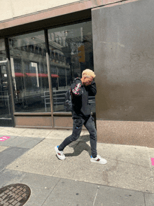 a person walking down a sidewalk with a sign on the wall that says ' no standing '