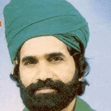 a man with a beard wearing a green turban .