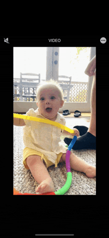 a baby is sitting on the floor playing with a hula hoop and the words video are above it