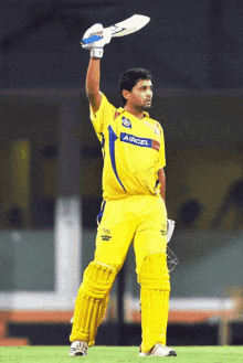 a cricket player wearing a yellow aircel jersey holds up his bat